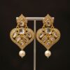 The earrings shown in the image are a style of traditional Indian jewelry known as Kundan or Polki earrings, often featuring a design with a pearl drop