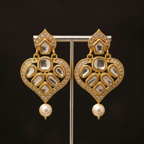The earrings shown in the image are a style of traditional Indian jewelry known as Kundan or Polki earrings, often featuring a design with a pearl drop